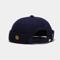 Close-up of navy blue brimless docker hat with yellow smiley face embroidery and metal buckle - Solid Smile Navy Blue