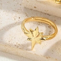 Makroaufnahme eines polierten goldenen Sternrings auf einer strukturierten beigen Steinfläche - Oktagramm-Stern-Stil