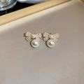 Détail de boucles d'oreilles nœud dorées avec perles pavées et pendentif en perle - Style Perle Nœud Doré