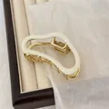 Elegant gold metal hair claw with cream white resin inlays on a jewelry tray - Cream
