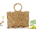 Detail of hand-woven straw tote bag with hollow circular patterns and ring handles - Tan