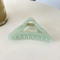Detail of light green triangular hair claw clip with golden spring on a white surface - Jelly Cyan