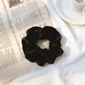 Classic black velvet scrunchie for hair styling placed on a decorative newspaper background - Black