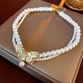 Macro detail of a double-layer necklace with golden butterfly and elegant pearls - Necklace-White