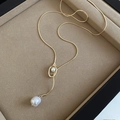 Dettaglio di una collana a Y dorata con perle barocche su un vassoio di velluto - Stile Cerchio di Perle / Oro