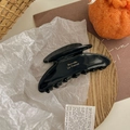 Détail d'une pince à cheveux noire brillante avec lettrage doré sur plateau bois - Noir