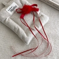 Detail einer beigen Stoff-Haarklammer mit roter Schleife und weichem Bommel-Dekor - Rot