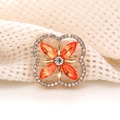 Detailed macro view of a gold four-leaf clover brooch with orange and clear crystals - Orange