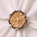 Handcrafted round rattan napkin ring with black woven edge detail on a white napkin - Round