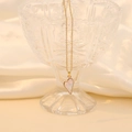 Macro view of gold asymmetric heart pendant necklace with pearlescent inlay on silk - White