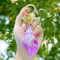 Regenboog conch sleutelhanger in paars-roze parelmoer met gouden ring en kleine bel - Paars