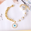 Bracelet perles baroques avec pendentif œil et chaîne dorée sur fond floral - Œil rond