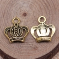Macro shot of two golden crown pendants showing detailed front texture and smooth back - Antique Gold