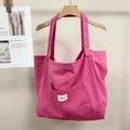 Detail of the pink canvas tote bag showing the front square pocket and brand label - Raspberry