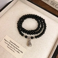 Macro shot of three-layer obsidian beaded bracelet with vintage silver lucky money bag charm - Black Agate Style (Lucky Bag)