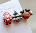 Detailed macro view of resin Santa, Christmas tree and elk hair clips on white card - Style 19 Christmas Hair Clip