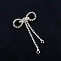 Broche de lazo plateado con diamantes de imitación brillantes y borlas en fondo de tela negra - Lazo Con Colgante De Anillo