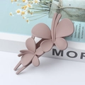 Elegant matte pink double butterfly hair clip displayed on a white decorative book - Khaki