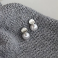 French style irregular pearl stud earrings with silver metal disks on grey background - White