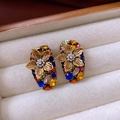 Details von Vintage-Ohrringen mit Perlen und bunten Kristallen auf weißem Samt - Gold