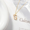 Detailed view of a gold G-letter necklace with a zircon-inlaid flower on a refined chain - Letter G