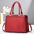 Détail du sac à main rouge en cuir grainé avec coutures en V et boucles dorées - Bordeaux