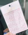Macro view of WG720 red 3D nail art stickers with cursive alphabet letters in packaging - Laser Red (WG720)
