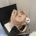 Light pink bucket bag with chain drawstring and plush charm on fashion magazine background - With Pendant / Pink