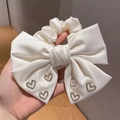 Detalle de lazo para el cabello en satén blanco con seis dijes de corazones de diamantes - Beige