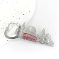 Close-up of London skyline metal bottle opener with red bus detail on a ceramic plate - Style 6 (Skyline Bottle Opener)