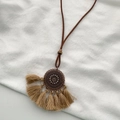 Detail of vintage bronze round pendant with intricate bohemian patterns and khaki tassels - Dreamcatcher Tassel Necklace / Bronze