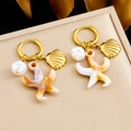 Macro shot of gold-plated starfish, conch, and pearl charms on a champagne display box - Shell and Star Style (E6242)