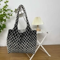 Detail of black and white wave pattern knit tote bag hanging on a white chair - Black Argyle