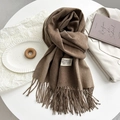 Detail of brown cashmere-like scarf with hand-tied tassels and white woven brand label - Mocha