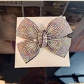 Detail shot of large crystal bow hair clip with iridescent rhinestones in a white box - Phantom AB Rhinestone