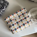 Detalle del bordado floral y etiqueta de tela en el neceser de lona para maquillaje - Fondo Beige Bordado Floral