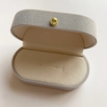 Macro shot of an oval light gray velvet jewelry gift box with a luxury gold metal clasp - 7.5*4.5*3.5cm / High-end Grey Velvet Box