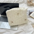 Macro view of cream quilted makeup bag with bunny embroidery and Sezakka brand label - Clutch Bag