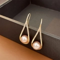 Macro view of gold-plated water drop earrings with pearls and crystals in a gift box - Gold Teardrop Hook