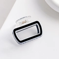 Detail view of a black and white rectangular hair claw clip with transparent top lever - Black