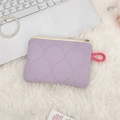 Detailed view of purple quilted cosmetic pouch with pink zipper on soft white texture - Light Purple