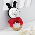 Close-up of handmade crochet baby rattle with red animal head and natural wooden ring - Ladybug
