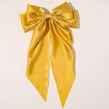 Detalle de la textura de tela satinada dorada brillante en un lazo grande para el cabello - Amarillo