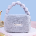 Chic grey plush handbag with fluffy faux fur ball handle and stylish brand patch - Gray