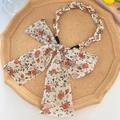 Floral print hairband featuring an elegant pearl gold chain and large fabric bow tie - White