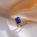 Macro shot of gold ring featuring rectangular blue gemstone and white zircon halo detail - Blue Gemstone Ring