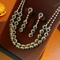 Close-up of gold flower necklace and earrings set with emerald green and clear crystals - Gold-Green