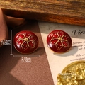 Détail macro de boucles d'oreilles émaillées rouges avec motif floral doré - Style Fleur Ronde en Émail Rouge (E4-20472C-6500)