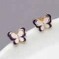 Macro shot of gold butterfly earrings with blue enamel wings and sparkling zircon center - Blue