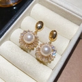 Macro view of 18k gold plated earrings with white pearl and sparkling zircon accents - Gold Round Style